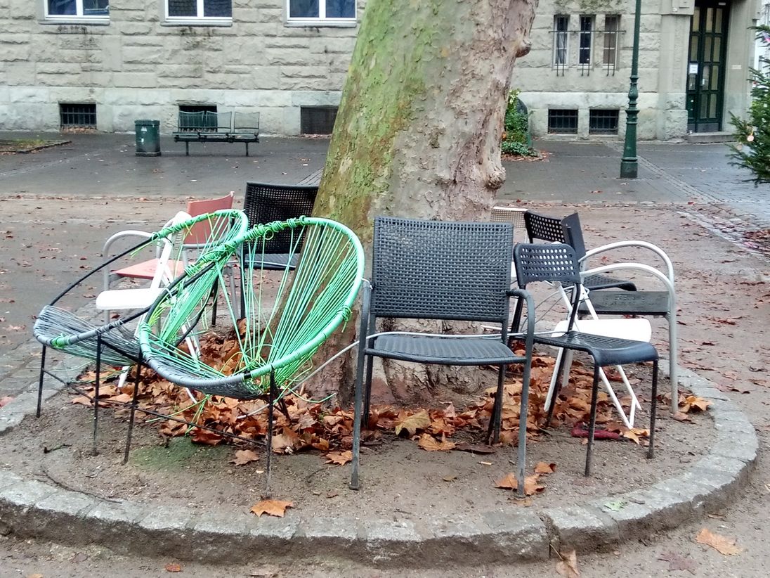 Das Bild zeigt Stühle an einem Baum, die symbolisch für den erhöhten Zulauf für Selbsthilfegruppen.